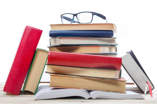 Pilha de livros e vidro sobre mesa de madeira isolada sobre fundo branco. De volta à escola. Espaço de cópia — Fotografia de Stock