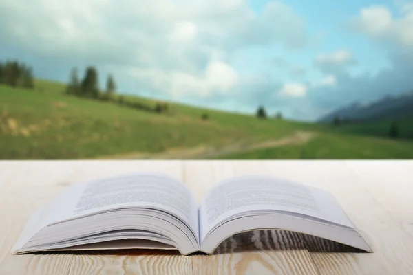 Open boek op houten tafel op natuurlijke onscherpe achtergrond — Stockfoto