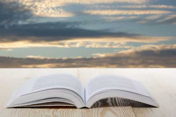 Open book on wooden table on natural blurred background — Stock Photo, Image