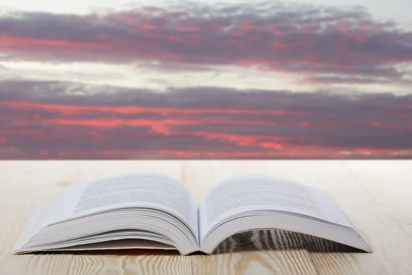 Open book on wooden table on natural blurred background — Stock Photo, Image