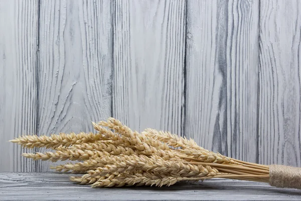木製のテーブルに小麦の穂。木材の背景上の小麦の束。収穫のコンセプト. — ストック写真