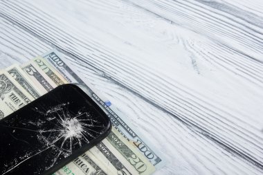 Modern kırık cep telefonu ve Beyaz ahşap zemin üzerinde para. Uzay kopyalayın. Üstten Görünüm