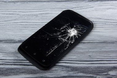 Modern cep telefonu Beyaz ahşap arka plan üzerinde kırık. Uzay kopyalayın. Üstten Görünüm