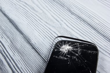 Modern cep telefonu Beyaz ahşap arka plan üzerinde kırık. Uzay kopyalayın. Üstten Görünüm