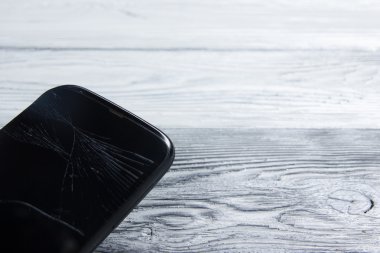 Modern cep telefonu Beyaz ahşap arka plan üzerinde kırık. Uzay kopyalayın. Üstten Görünüm