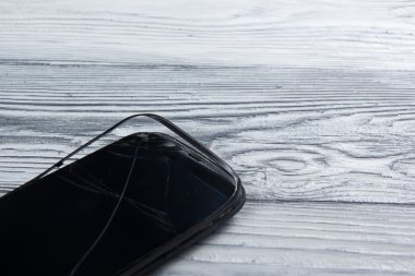 Modern cep telefonu Beyaz ahşap arka plan üzerinde kırık. Uzay kopyalayın. Üstten Görünüm