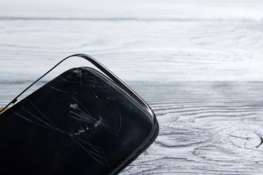 Modern cep telefonu Beyaz ahşap arka plan üzerinde kırık. Uzay kopyalayın. Üstten Görünüm