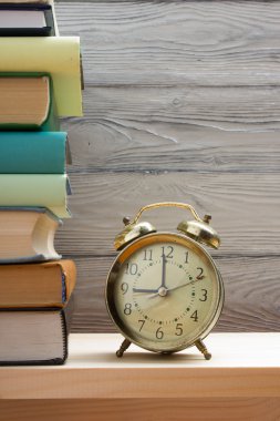 Renkli kitaplar ve çalar saat ahşap masa yığını. Okula dönüş. Kopya alanı