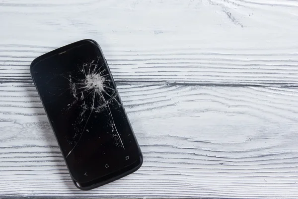 Modern cep telefonu Beyaz ahşap arka plan üzerinde kırık. Uzay kopyalayın. Üstten Görünüm