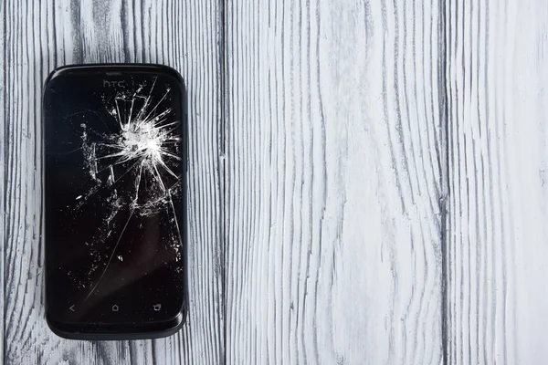 Modern cep telefonu Beyaz ahşap arka plan üzerinde kırık. Uzay kopyalayın. Üstten Görünüm