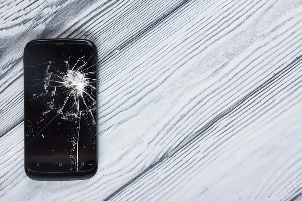 Moderno telefone celular quebrado no fundo de madeira branca. Espaço para cópia. Vista superior — Fotografia de Stock