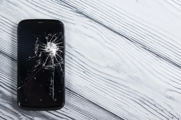 Modern cep telefonu Beyaz ahşap arka plan üzerinde kırık. Uzay kopyalayın. Üstten Görünüm