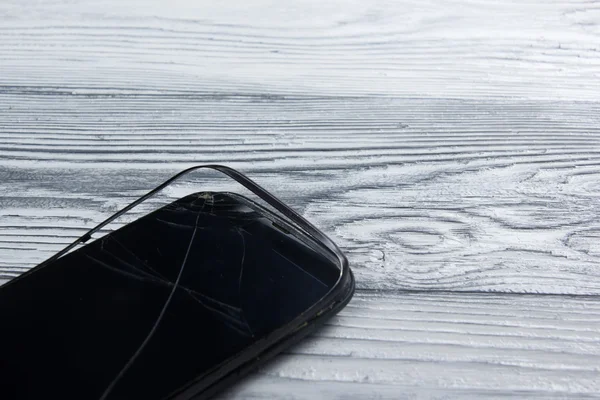 Modern cep telefonu Beyaz ahşap arka plan üzerinde kırık. Uzay kopyalayın. Üstten Görünüm