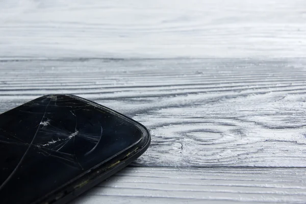 Modern cep telefonu Beyaz ahşap arka plan üzerinde kırık. Uzay kopyalayın. Üstten Görünüm