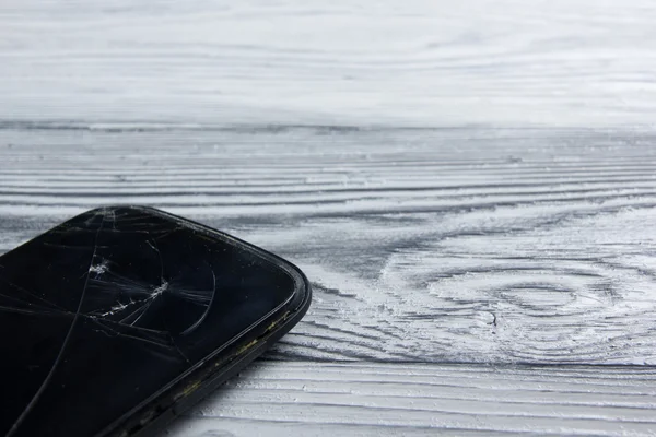 Modern cep telefonu Beyaz ahşap arka plan üzerinde kırık. Uzay kopyalayın. Üstten Görünüm