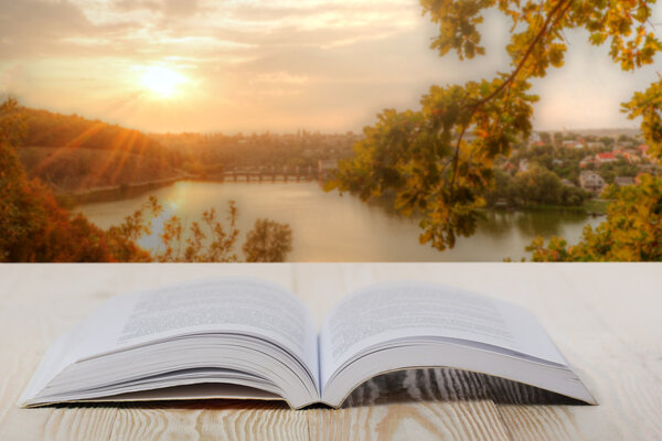 Открытая книга на деревянном столе на естественном размытом фоне. Возвращайся в школу. Копировальное пространство
