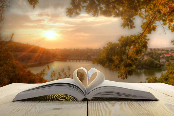 Open book on wooden table on natural blurred background. Heart book page. Back to school. Copy Space