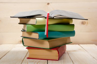 Renkli kitaplar, açık kitap ve ahşap masa bardakta yığını. Okula dönüş. Kopya alanı