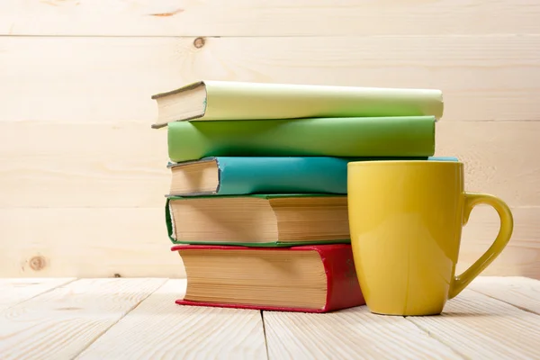 Pila di libri colorati e tazza su tavolo in legno. Torniamo a scuola. Copia spazio — Foto Stock