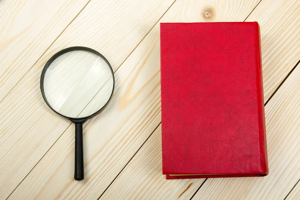 Composition with hardback book and magnifying glass on the table. Back to school, copy space. Education background. — Stock Photo, Image