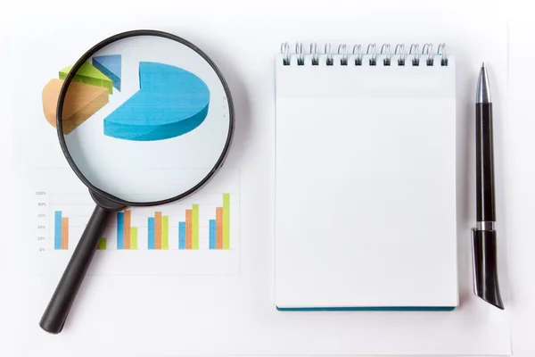 Finansal muhasebe hisse senedi grafikleri analiz. Büyüteç camı, defter kağıt, kalem grafiği boş levha ile. Üstten Görünüm