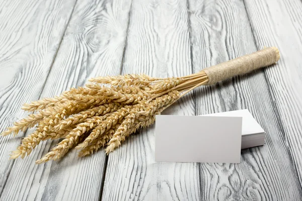 空白の名刺と木製のテーブルに小麦の穂。木材の背景上の小麦の束。収穫のコンセプト. — ストック写真
