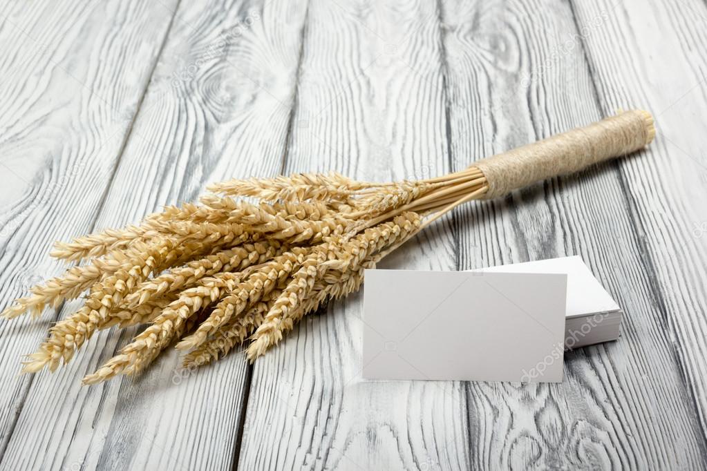 Wheat Ears on Wooden Table with blank business cards. Sheaf of Wheat over Wood Background. Harvest concept.