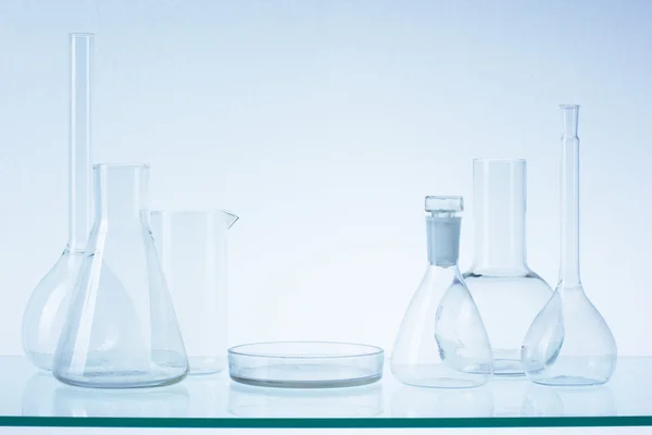 Diverse tomma Laboratorieartiklar av glas, provrör. Blå ton medicinsk bakgrund. Kopiera utrymme — Stockfoto