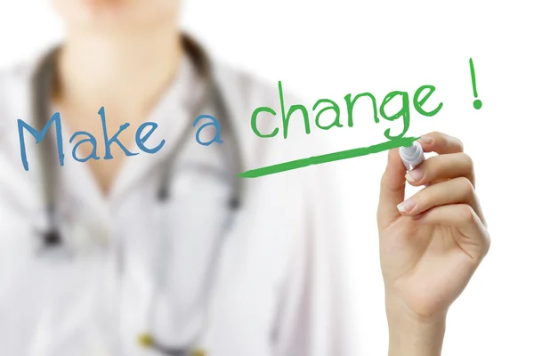 Female doctor with stethoscope writing "Make a change !" . Hand holding pen isolated on white. Medical background. — Stock Photo, Image