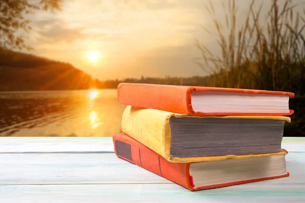 Pila di libri colorati su tavolo in legno su sfondo naturale sfocato. Torniamo a scuola. Copia spazio — Foto Stock