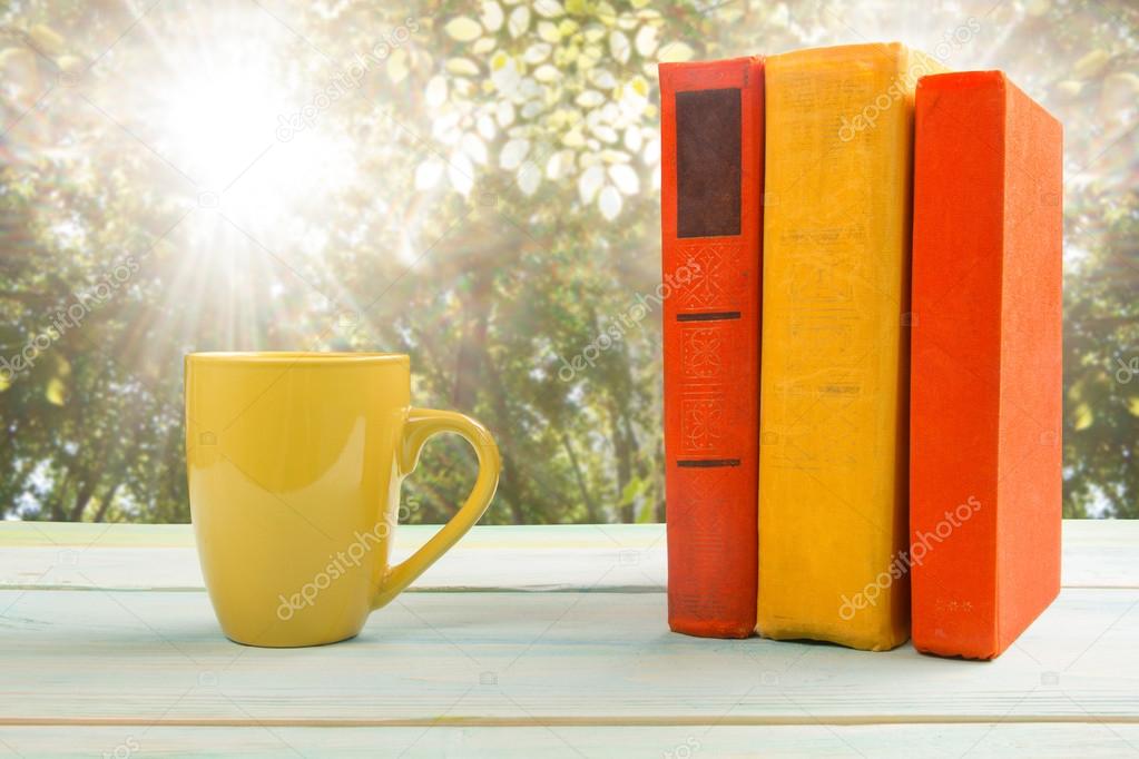 Stack of colorful bookStack of colorful books and cup on wooden table on natural blurred background. Back to school. Copy spaces and cup on wooden table on natural blurr