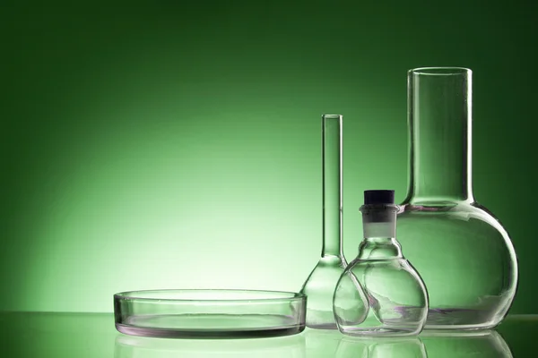 Assorted empty laboratory glassware, test-tubes. Green tone medical background. Copy space for text. — Zdjęcie stockowe