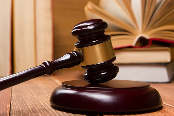 Boek van de wet met houten rechters hamer op tafel in een rechtszaal of wet tenuitvoerleggingsdienst. — Stockfoto