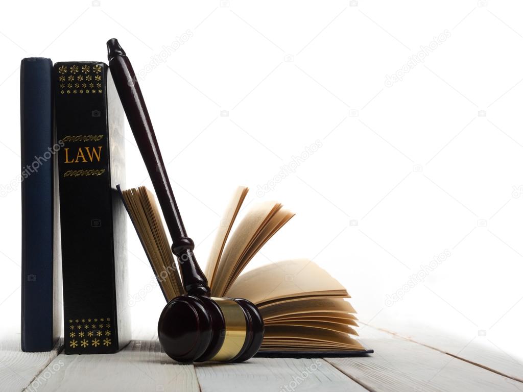 Open law book with wooden judges gavel on table in a courtroom