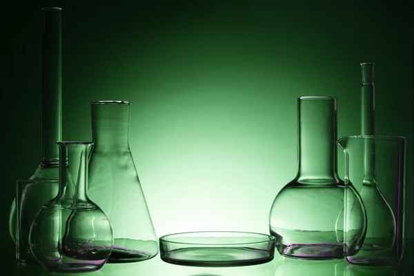 Assorted empty laboratory glassware, test-tubes. Green tone medical background. Copy space for text. — Stockfoto