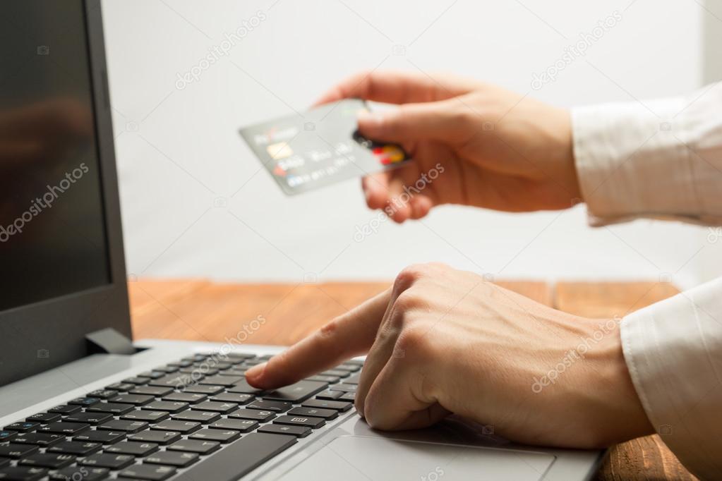 Hands holding credit card typing numbers on tablet pc making online payment at home the wooden table. Online shopping concept. Selective focus.