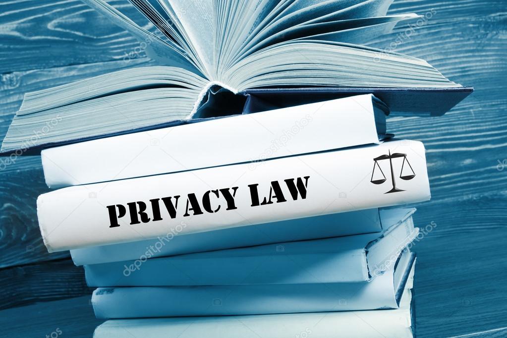 Book with Privacy Law word on table in a courtroom or enforcement office. Toned image