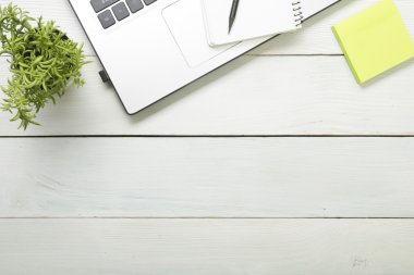 Office desk table with supplies. Top view. Copy space for text. Laptop, blank notepad, pen,  reminder, flower.