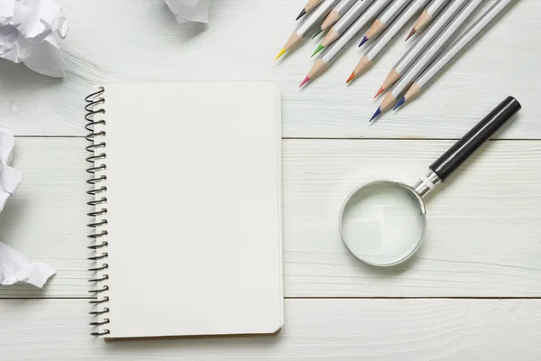 Zerknüllte Papierkugeln, Lupen, Bleistifte und Notizbuch mit weißem Blatt auf dem Holztisch. Konzept zur Kreativitätskrise — Stockfoto