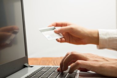 Hands holding credit card typing numbers on tablet pc making online payment at home the wooden table. Online shopping concept. Selective focus.