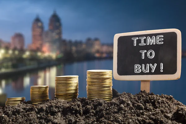 Time to buy - Financial opportunity concept. Golden coins in soil Chalkboard on blurred urban background — Stockfoto