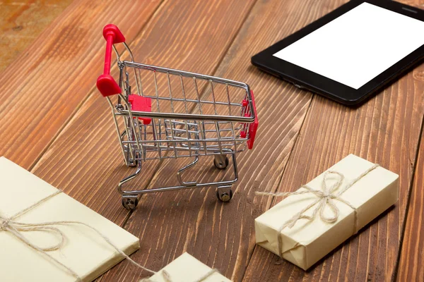 Online vásárlás koncepció - bevásárló kosár ürítése, laptop és tabletta pc, díszdobozban, rusztikus, fából készült háttér — Stock Fotó