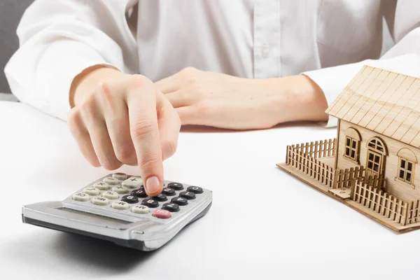 Real estate concept - businessman counting behind home architectural model — Stock Fotó