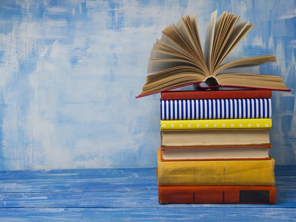 Open book, hardback books on abstract blue background at wooden table. Back to school. Copy space for text