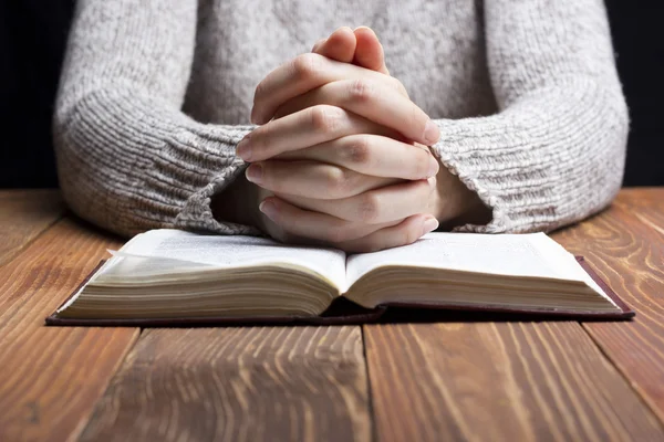 İçinde karanlık bir İncil ile ahşap masa üzerinde dua eller kadın