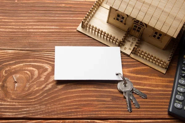 Real Estate Concept. Model house, keys, blank business card and calculator on wooden table. Top view. — 图库照片