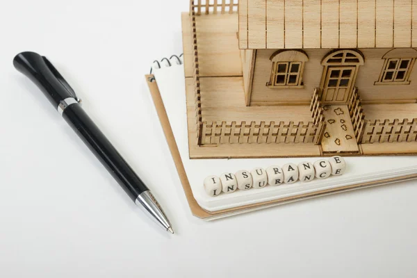 Concept of housing purchase and insurance. Office desk table with supplies top view. Pen, notepad, model house, wooden block word — 图库照片