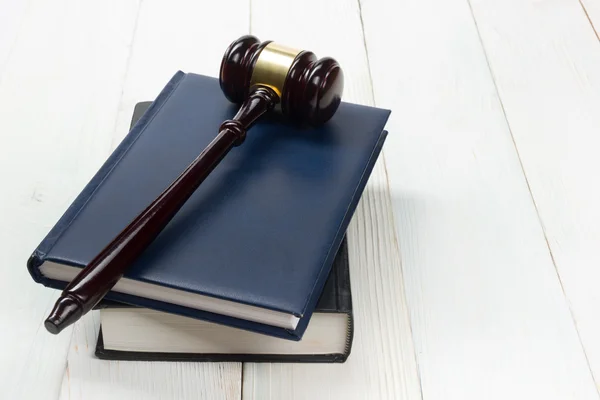 Open law book with wooden judges gavel on table in a courtroom