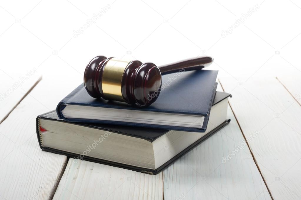 Open law book with wooden judges gavel on table in a courtroom