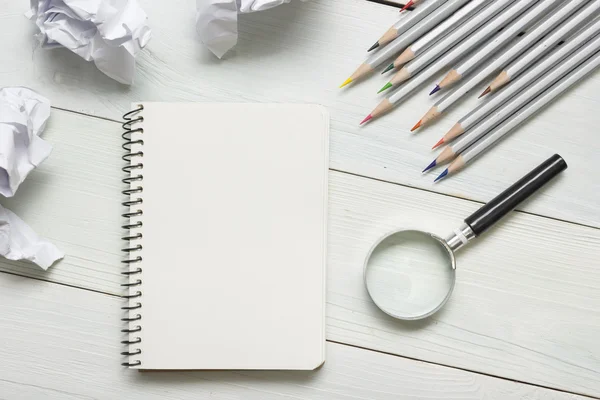 Boules de papier froissées, loupe, crayons et cahier avec feuille blanche vierge sur table en bois. Concept de crise de la créativité — Photo